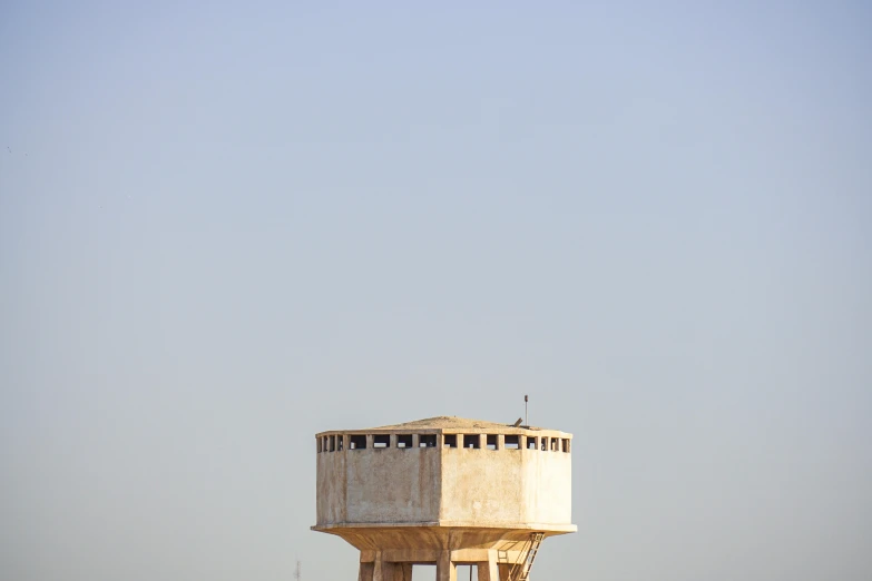 a water tower in the middle of a body of water, unsplash, minimalism, citadel of erbil, square, wooden, beige