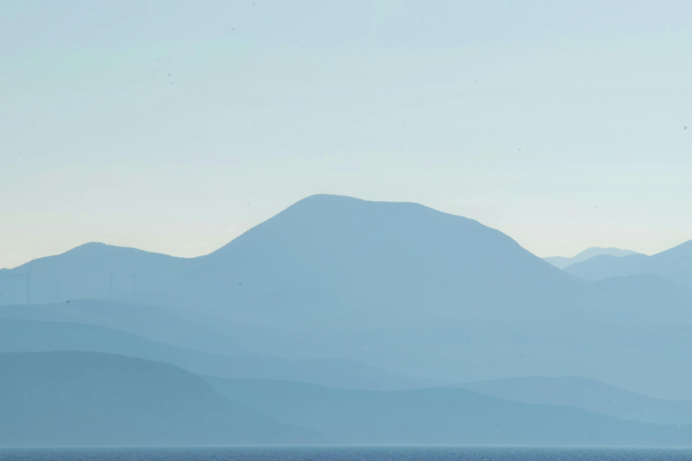 a large body of water with mountains in the background, by Exekias, minimalism, blue image, slide show, telephoto, in muted colours