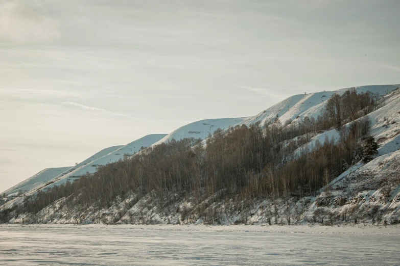 a man riding a snowboard down a snow covered slope, an album cover, inspired by Konstantin Vasilyev, pexels contest winner, mountains river trees, norilsk, seen from afar, close river bank