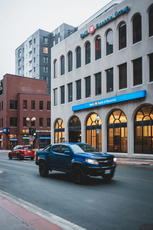 a blue car driving down a street next to tall buildings, minneapolis, set inside of the bank, storefront, 2019 trending photo