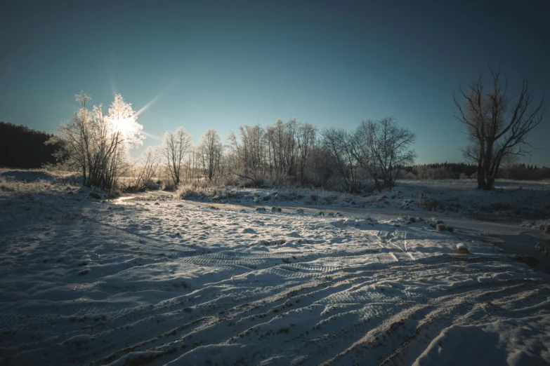 a man riding a snowboard down a snow covered slope, a picture, unsplash, land art, swedish countryside, sun glare, frozen river, (3 are winter