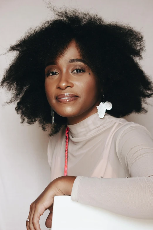 a woman sitting on top of a white chair, by Lily Delissa Joseph, pexels contest winner, afrofuturism, dark short curly hair smiling, fluffy hair, headshot profile picture, sza