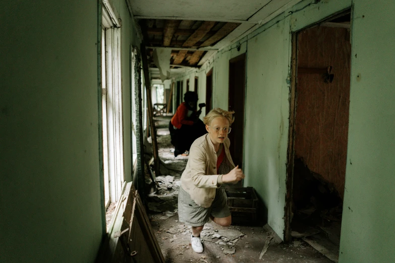 a woman standing in a hallway next to a window, by Lee Gatch, destroying houses, 1990s photograph, walking boy, national geography photography