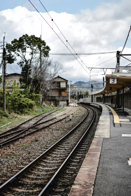 a train station with a train on the tracks, by Sengai, unsplash, sōsaku hanga, square, landscape photo, panorama, fujifilm”