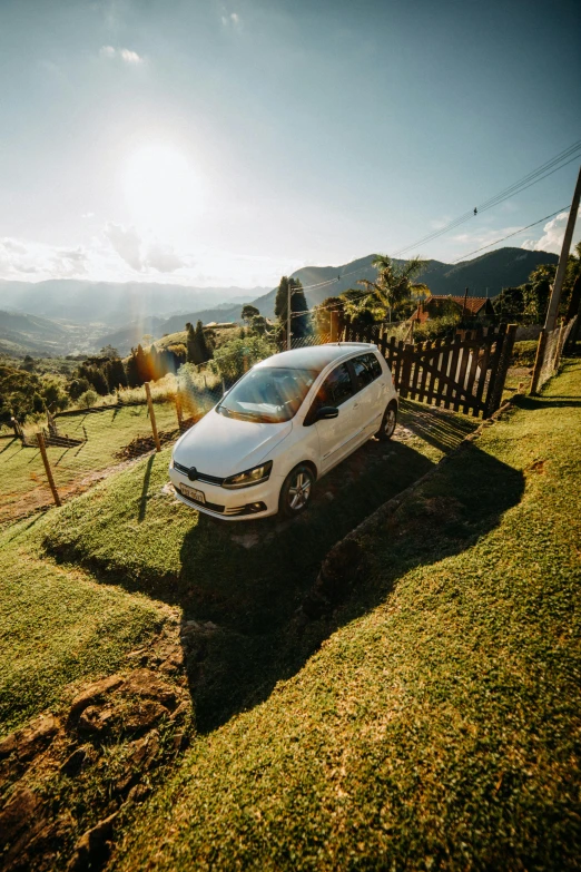 a white car parked on the side of a road, by Felipe Seade, pexels contest winner, on a green hill, garden, 4k panoramic, warm light