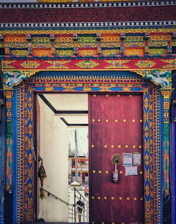 a red door sitting in the middle of a building, cloisonnism, highly intricate in technicolor, thangka, 2019 trending photo, bhutan