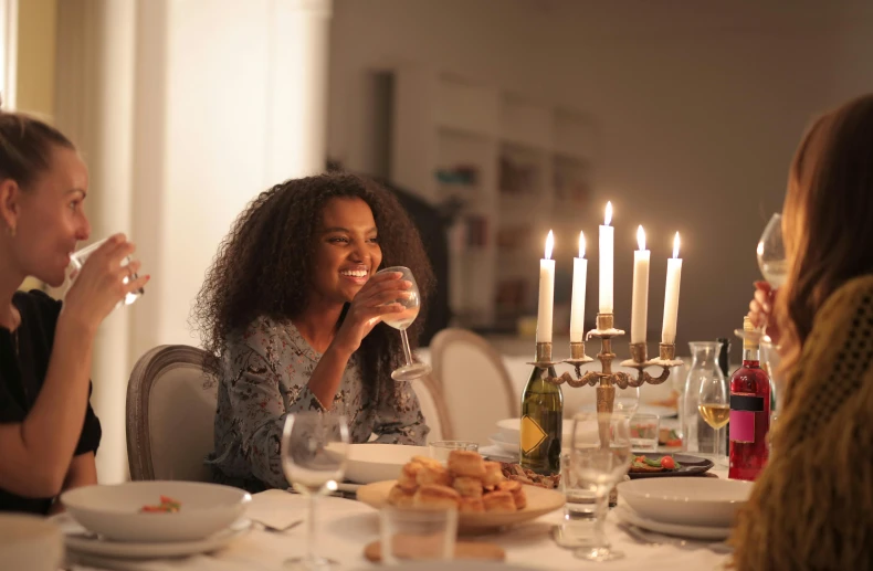 a group of people sitting around a dinner table, on a candle holder, ashteroth, drinking champagne, natural candle lighting