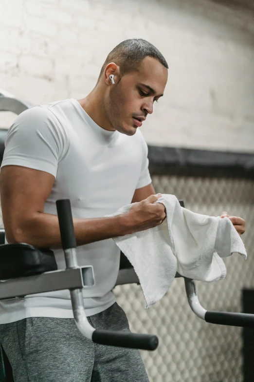 a man holding a towel in a gym, happening, square, earbuds, compression, industries