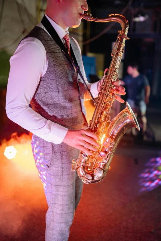 a man in a vest and tie playing a saxophone, pexels, happening, night clubs and neons, the scooter ( edm band, fire lit, ornately dressed