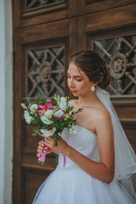 a woman in a wedding dress holding a bouquet, by Antoni Brodowski, pexels contest winner, leaning on door, beautiful well rounded face, ivan aivazovski, outside view