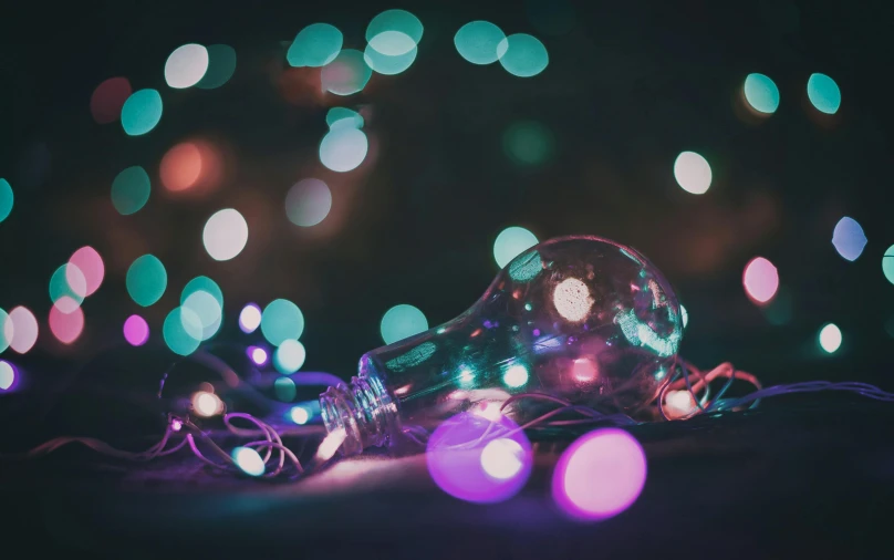 a light bulb sitting on top of a table, a hologram, pexels contest winner, fairy lights, purple and blue colour palette, christmas lights, rim lights purple and green