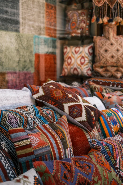 a room filled with lots of different colored rugs, inspired by Riad Beyrouti, trending on unsplash, pillows, market stalls, brown, greek fabric