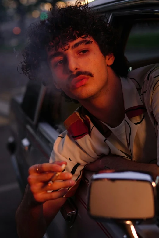 a man sitting in a car smoking a cigarette, an album cover, inspired by Nan Goldin, trending on pexels, mexican mustache, finn wolfhard, arab, ( ( theatrical ) )