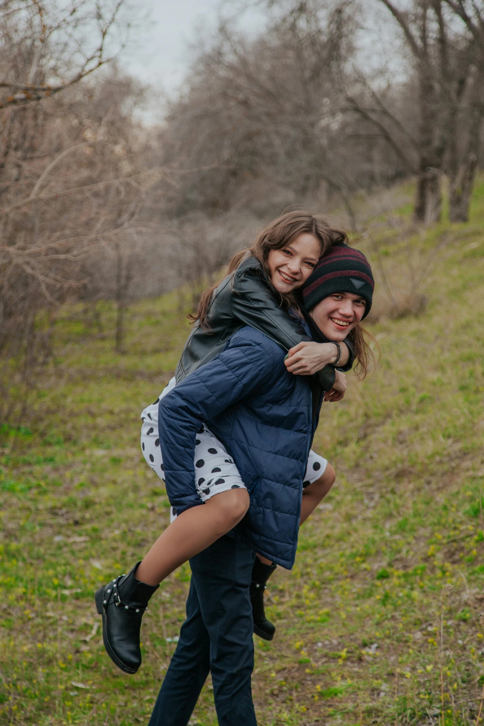 a couple of people that are standing in the grass, pexels contest winner, action shot girl in parka, teen boy, on a green hill between trees, riding