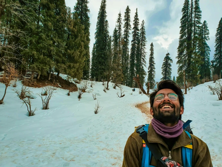 a man that is standing in the snow, a picture, inspired by Kailash Chandra Meher, pexels contest winner, solo hiking in mountains trees, giddy smirk, psychedelic lush pine forest, wearing dirty travelling clothes