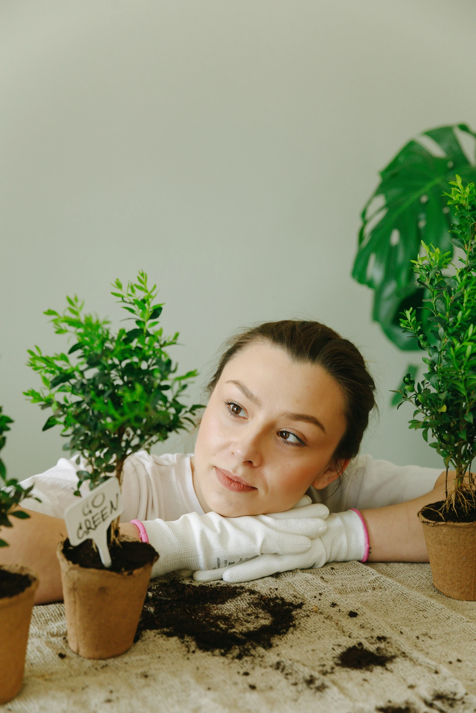 a woman sitting at a table with potted plants, trees growing on its body, thoughtful pose, trending photo