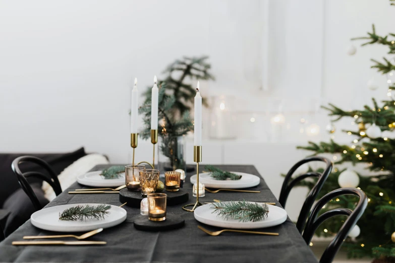 a dining room table with a christmas tree in the background, inspired by Ernest William Christmas, trending on unsplash, baroque, gold and black metal, brass plates, set against a white background, subtle atmospheric lighting