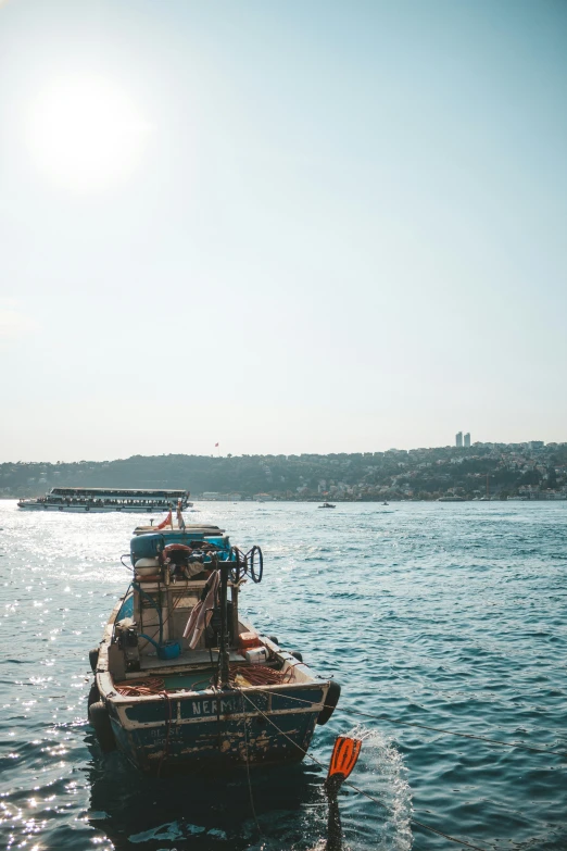 a small boat floating on top of a body of water, by Niyazi Selimoglu, hurufiyya, istanbul, sunny day time, slide show, color graded