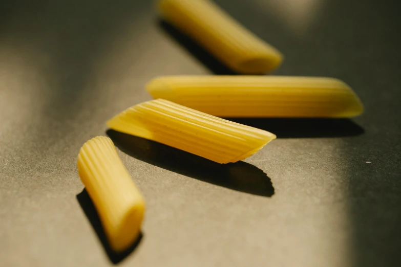 three pieces of pasta sitting on top of a table, a macro photograph, by Carey Morris, trending on pexels, yellow charcoal, small quills along it's back, very elongated lines, miniature product photo