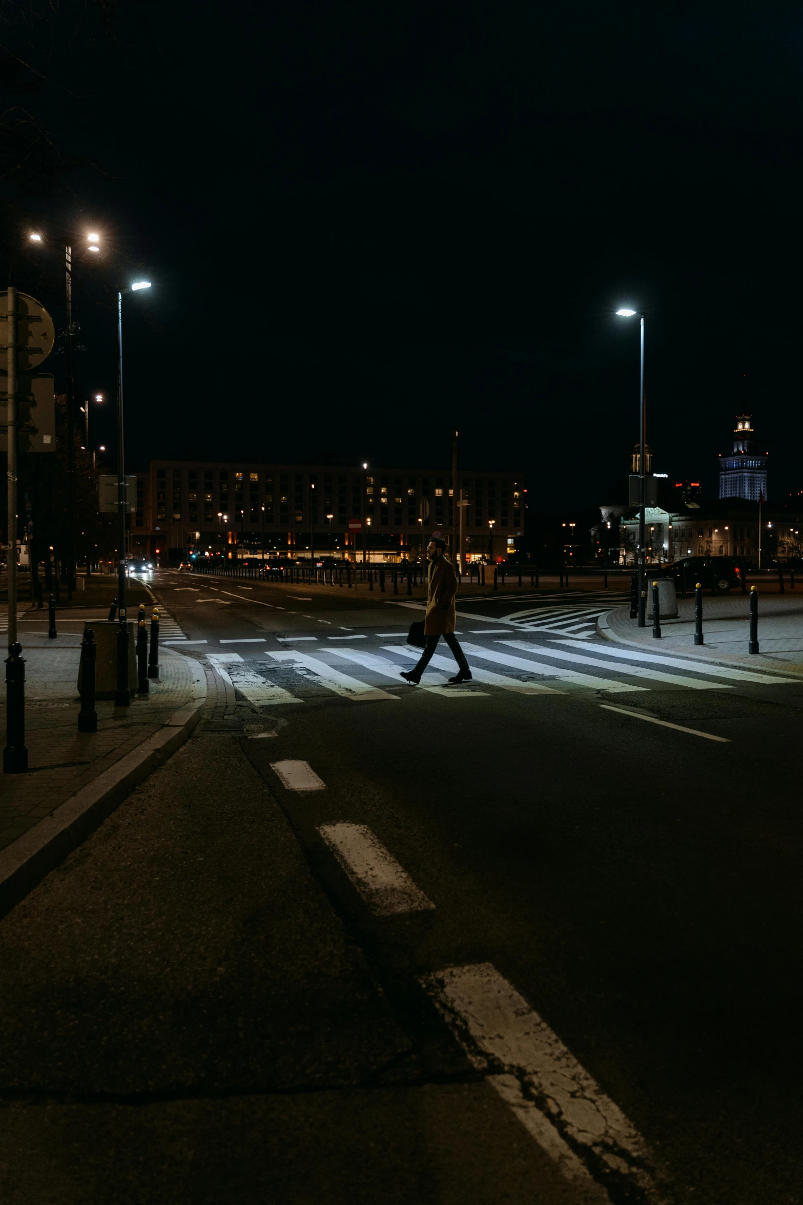 a person walking across a street at night, by Tobias Stimmer, pexels contest winner, happening, espoo, intersection, harsh light, deserted