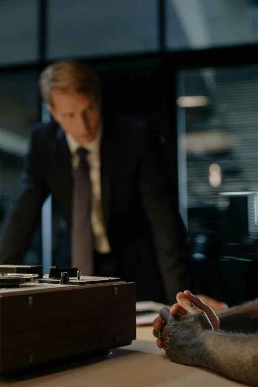 a monkey sitting on a table next to a man in a suit, unsplash, still image from tv series, investigation, hands on counter, david fincher