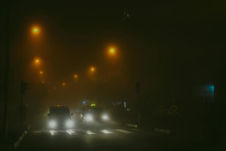 a group of cars driving down a street at night, inspired by Elsa Bleda, pexels contest winner, tonalism, dense volumetric fog, silent hill landscape, yellow volumetric fog, atmospheric lighting - n 9