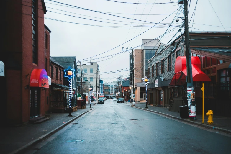 a street filled with lots of traffic next to tall buildings, by Carey Morris, pexels contest winner, graffiti, rhode island, warm street lights store front, western town, rain aesthetic