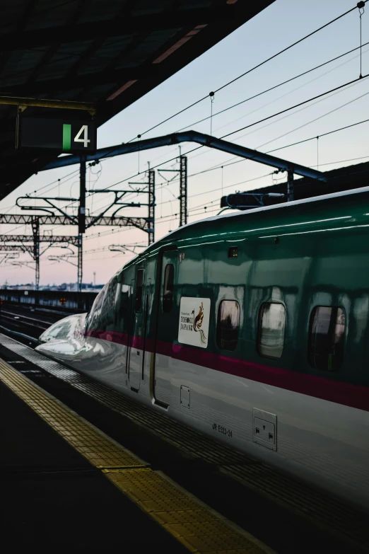 a train pulling into a train station next to a platform, inspired by Kinichiro Ishikawa, unsplash, draped in pink and green robes, skyline showing from the windows, going forward to the sunset, fujifilm