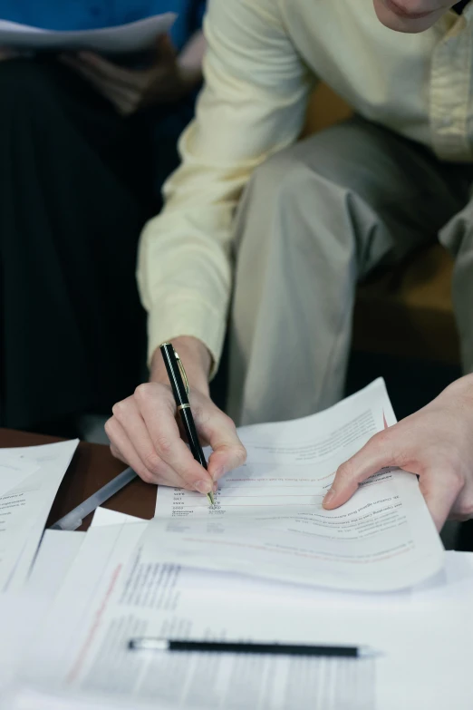 a woman sitting at a table with papers and a pen, trending on reddit, high quality photo, lgbtq, inspect in inventory image, full frame image