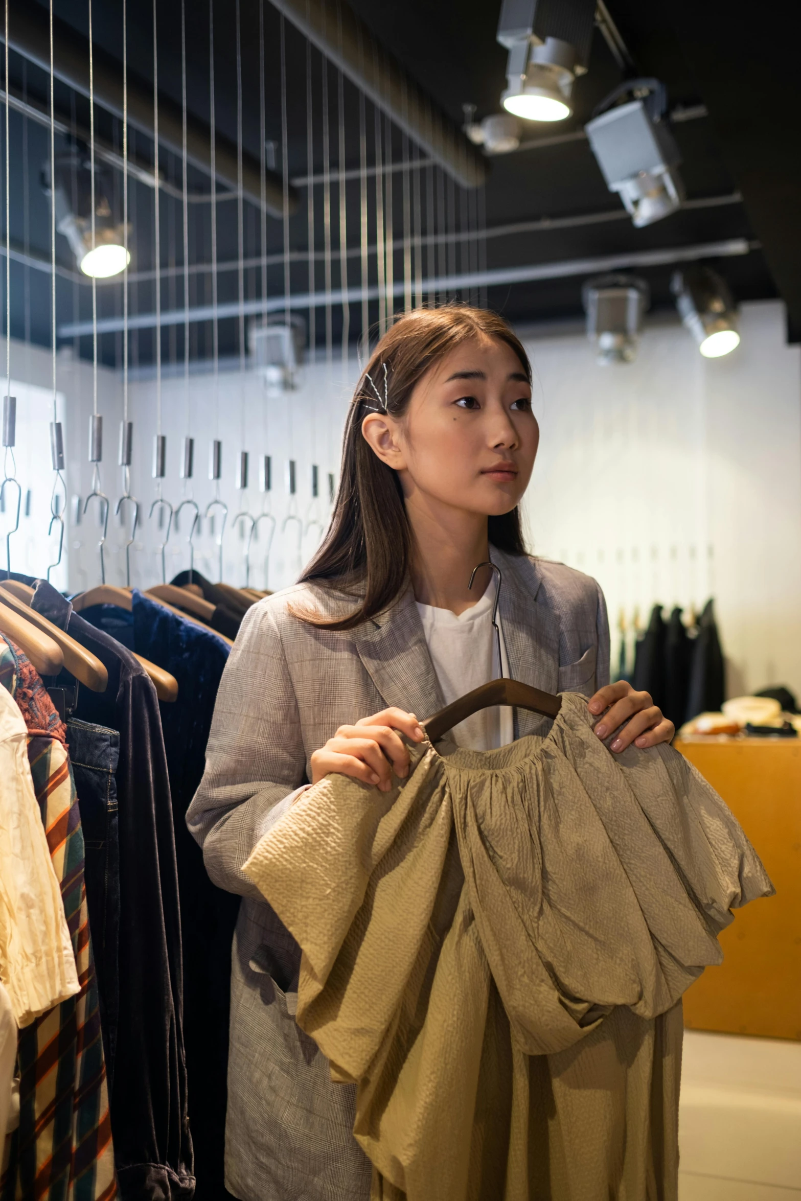 a woman standing in front of a rack of clothes, wearing a worn out brown suit, japanese collection product, inspect in inventory image, curated collections