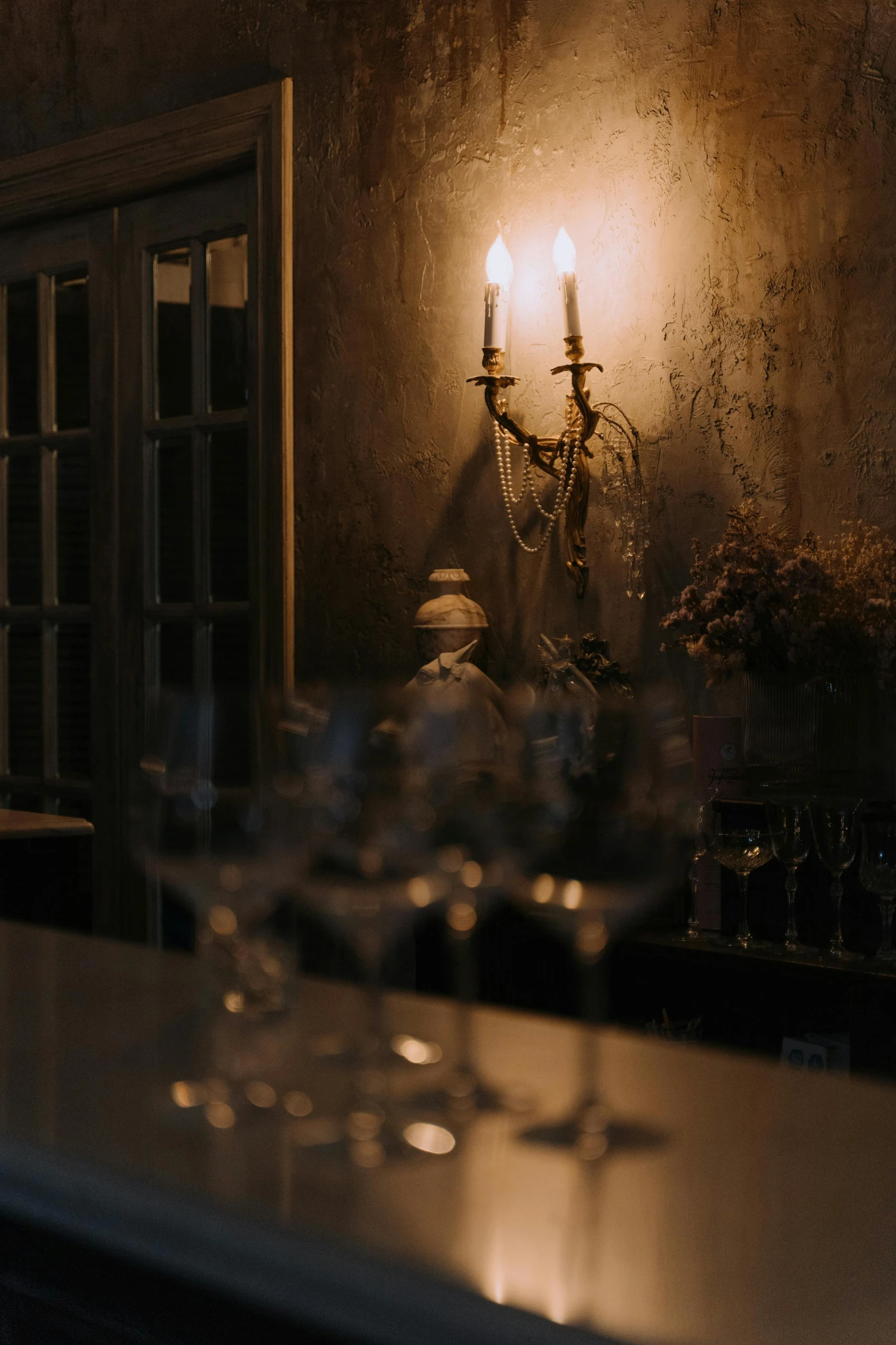 a couple of wine glasses sitting on top of a counter, inspired by Elsa Bleda, australian tonalism, gothic mansion room, sconces, cafe lighting, looking off to the side