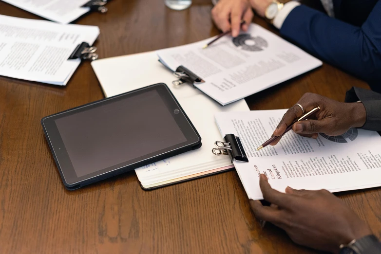 a group of people sitting around a wooden table, holding a clipboard, close up to the screen, multiple stories, thumbnail