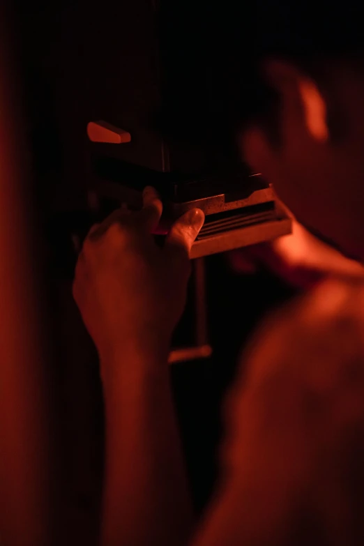 a man playing the piano in a dark room, inspired by Nan Goldin, happening, holding a glock, shot on red camera, crimson themed, pictured from the shoulders up