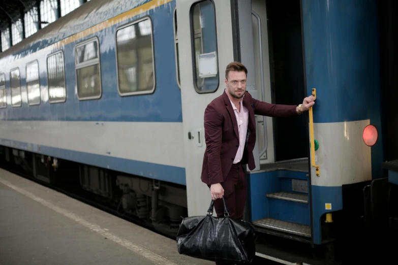 a man that is standing next to a train, by Adam Marczyński, happening, tailored clothing, thumbnail