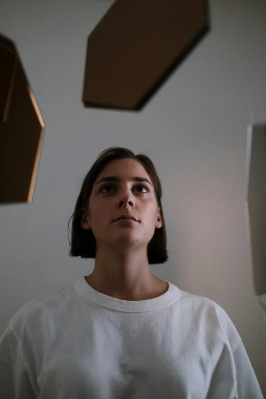 a woman in a white shirt looking up, by Attila Meszlenyi, unsplash, hyperrealism, in a room, low quality photo, cardboard, square face