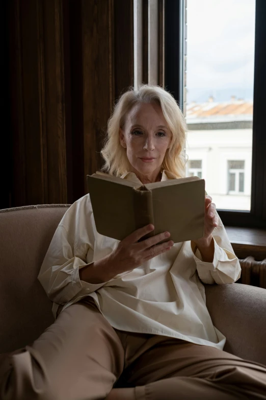 a woman sitting on a couch reading a book, a portrait, by Dietmar Damerau, pexels contest winner, albino, movie still, square, angelina stroganova