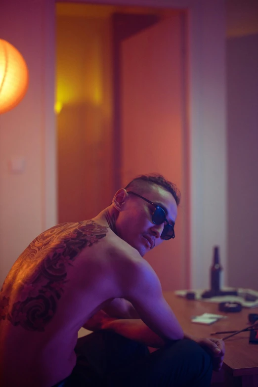 a shirtless man sitting on top of a wooden table, a tattoo, unsplash, process art, 8 0 s asian neon movie still, hotel room, shades, shaved sides