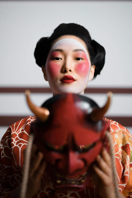 a close up of a person holding a mask, a picture, inspired by Tosa Mitsunobu, red lipstick on face, an ox, ( ( theatrical ) ), promo photo