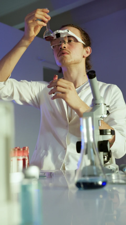 a man in a lab coat using a microscope, by Adam Marczyński, pexels, performing on stage, julian ope, student, gif