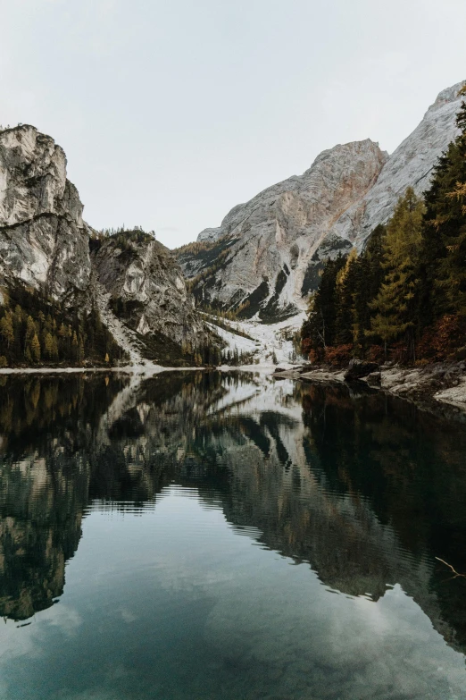 a body of water with a mountain in the background, by Sebastian Spreng, pexels contest winner, lago di sorapis, detailed trees and cliffs, muted water reflections, panoramic