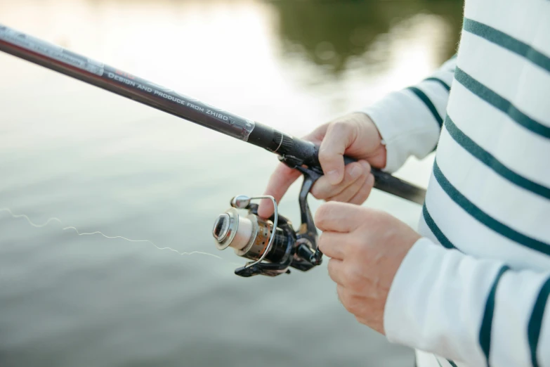 a close up of a person holding a fishing rod, at the waterside, zoomed in, modelling, easy to use