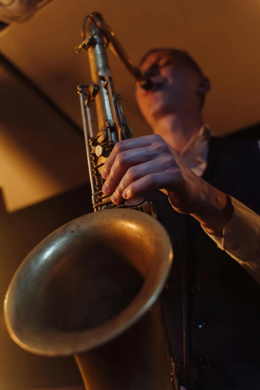 a man playing a saxophone in a dimly lit room, an album cover, unsplash, photorealism, brass beak, sydney hanson, detail shot, 15081959 21121991 01012000 4k