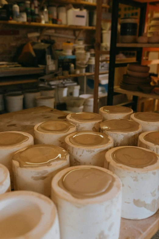 a bunch of pots sitting on top of a table, in a workshop, brown holes, creamy, made of glazed