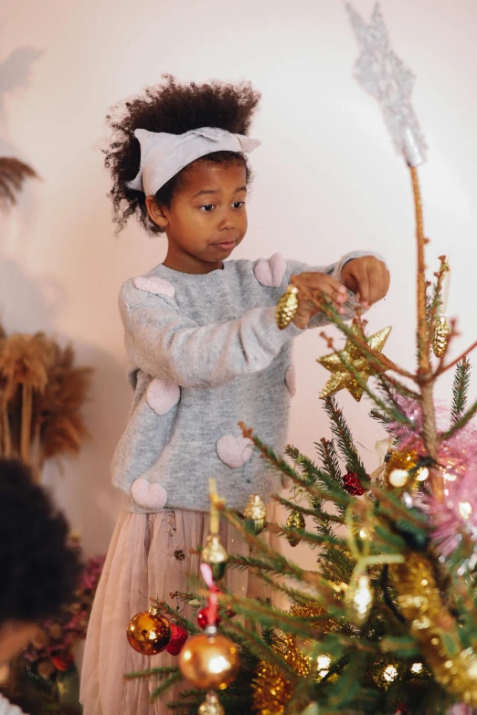 a little girl decorating a christmas tree, by Lucette Barker, pexels, process art, portrait willow smith, delicate embellishments, sweater, pastel hues