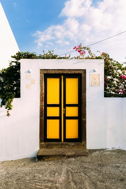 a yellow door sitting on the side of a white building, by Julia Pishtar, unsplash, santorini, black. yellow, square, azores