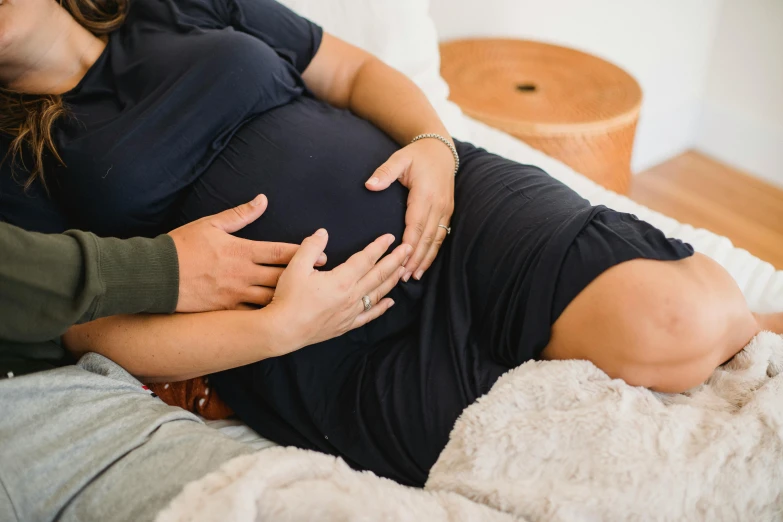 a pregnant woman laying on a bed next to a man, pexels contest winner, happening, manuka, comforting and familiar, cast, bump mapped