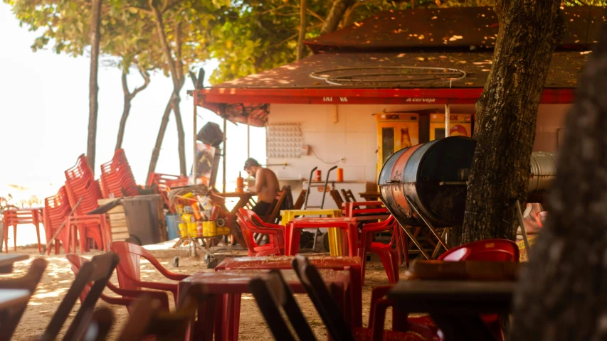 a group of red chairs sitting on top of a sandy beach, sitting at a bar, edu souza, barbecue, real congas