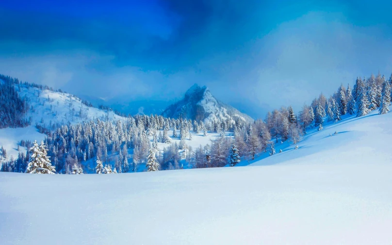 a man riding skis down a snow covered slope, by Cedric Peyravernay, pexels contest winner, romanticism, spruce trees, vibrant blue, panorama, a cozy