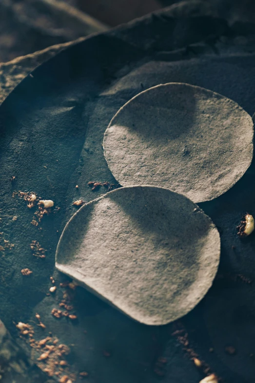 a close up of a plate of food on a table, an album cover, inspired by Carpoforo Tencalla, unsplash, conceptual art, shell craters, tacos, partially covered with dust, slate