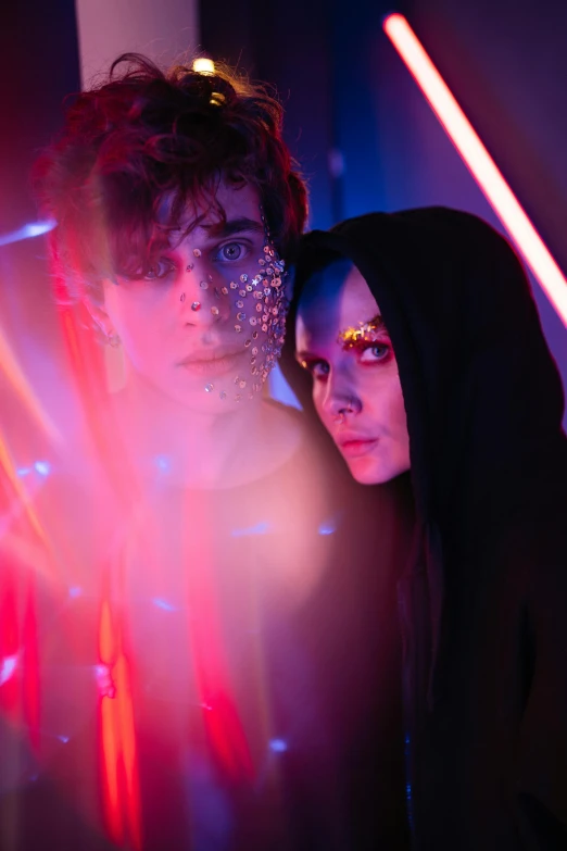 a man and a woman standing next to each other, an album cover, by Julia Pishtar, pexels contest winner, glowing magenta laser eyes, covered in circuitry, red and blue black light, ( ( theatrical ) )